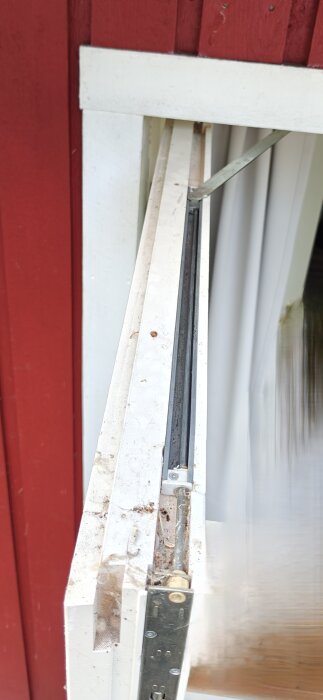 Närbild av en dörr som är hängd på gångjärn på sidan av en röd vägg, detalj av dörrkarmen och lådan på 450 mm.