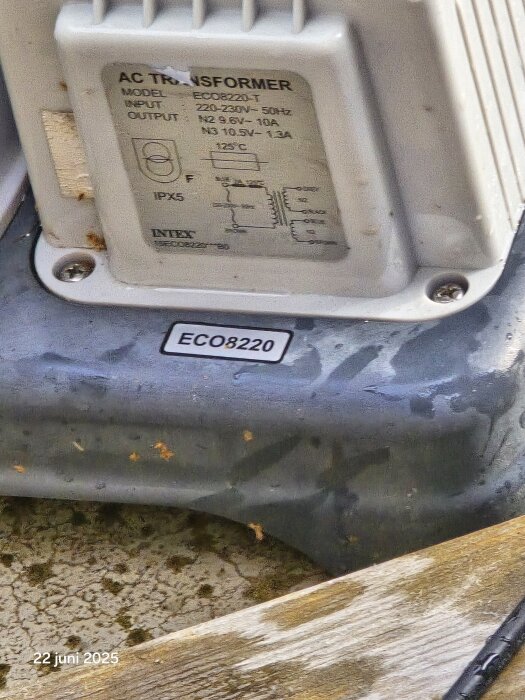 AC-transformator modell ECO8220 på en våt yta, märkning och specifikationer synliga.