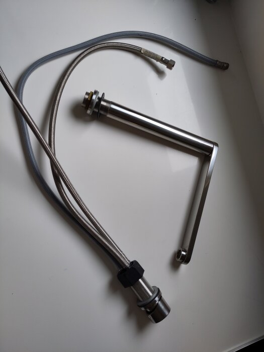 Begagnad köksblandare med metallslangar och kran, visas på vit bakgrund. 12 år gammal, säljes för 500 kronor.