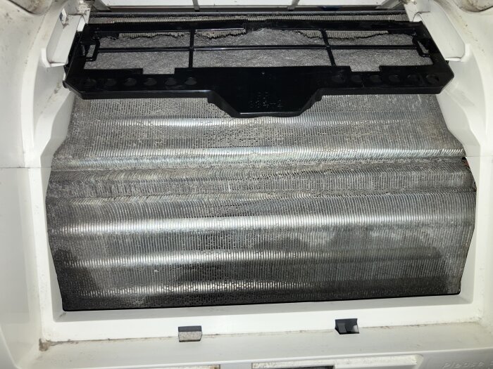 Närbild av en luftkonditioneringsenhet med smutsiga lameller som verkar uppbyggda av smuts trots användning av rengöringsspray.