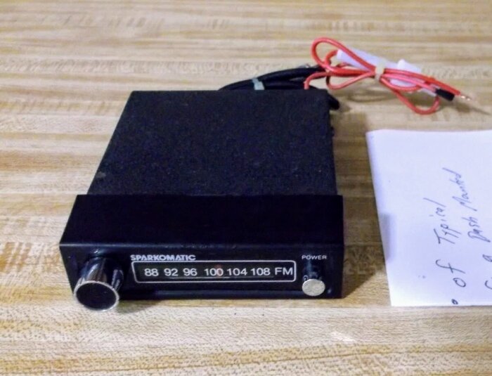 FM-konverter med frekvensskala från Spark-o-matic, placerad på ett trämönstrat bord, med röda och svarta kablar anslutna.