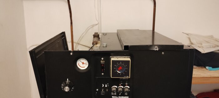 Värmepanna med kontrollpanel och rör ovanpå, inkluderande en tryckmätare och vred, som diskuterats i ett forum om byte av beredare.