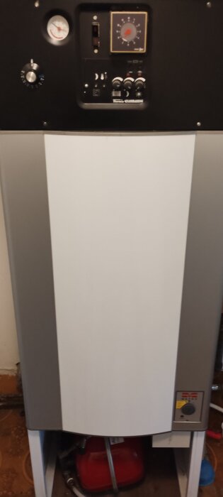 Värmepanna med tryckmätare och kontrollpanel ovanpå, samt expanderkärl nedtill.