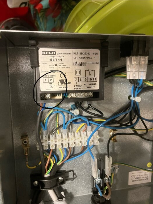 Inre del av en elektrisk enhet med kablar och termistorkabeln märkt "probe" i svart cirkel.