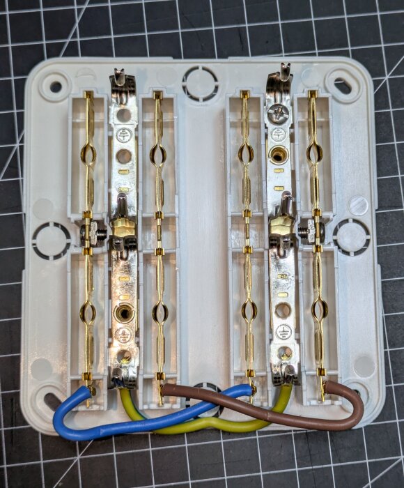 4-vägs eluttag med synliga ledningar, blå och bruna kablar är anslutna. Produkten beskrivs som av låg kvalitet.