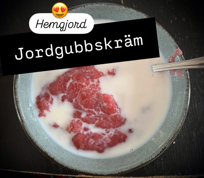 Hemgjord jordgubbskräm i en tallrik med mjölk och en sked.