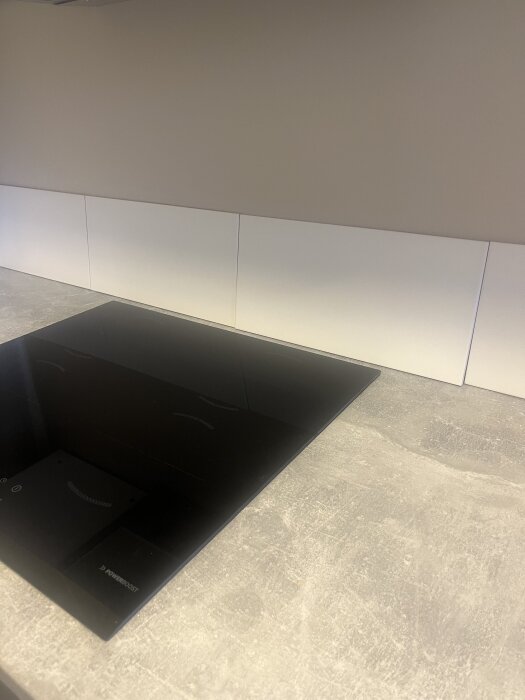 Vita kakelplattor uppställda längs en köksvägg bakom en spis, redo att monteras som stänkskydd.