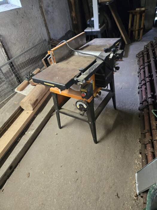 Bordssåg i snickarverkstad med träplankor och verktyg runtom.