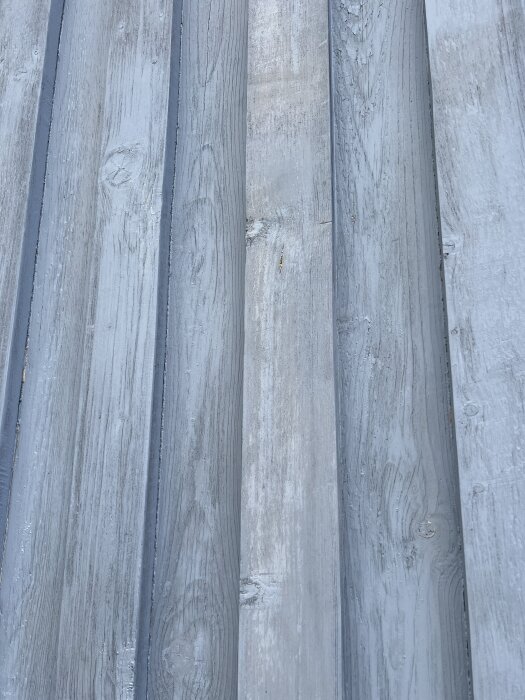 Garagedörrar med flagnande grå färg visar tecken på vittring och åldrande träpanel.