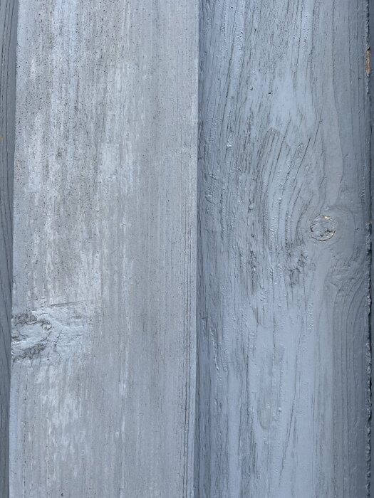 Avflagnad grå färg på trävägg, med en synlig träknut.