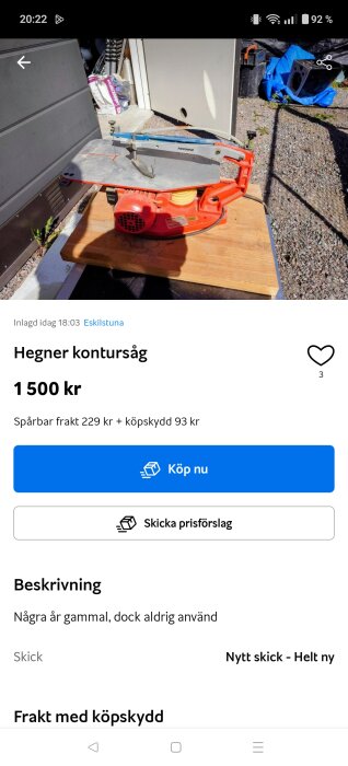 Röd-orange Hegner kontursåg på ett träbord utomhus, omgiven av verktyg och byggutrustning.