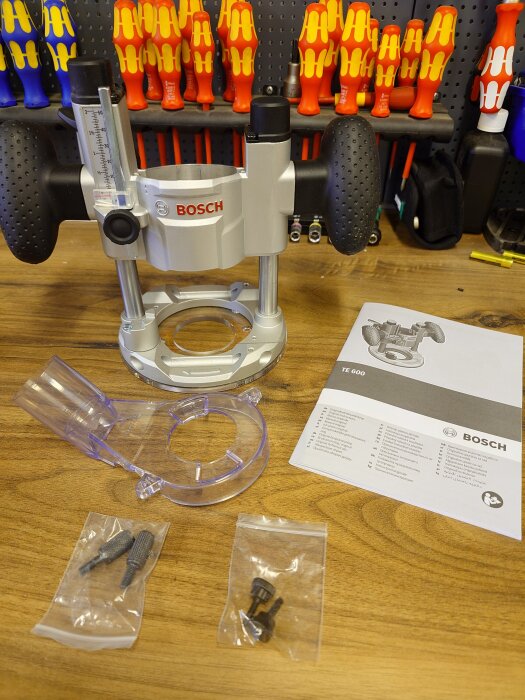 Bosch sänkenhet med handtag och tillbehör på en arbetsbänk, omgiven av skruvmejslar i bakgrunden.