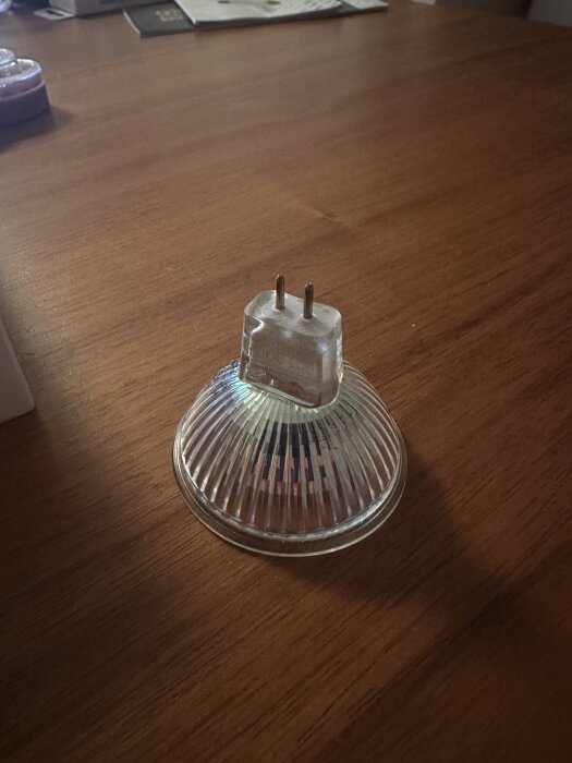 En halogenlampa med två stift på en trären yta.