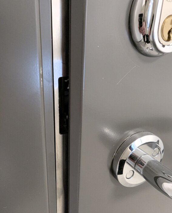 Dörr med synligt glapp vid handtaget, elektroniskt lås ovanför. Verkar felmonterat med utrymme för verktyg.