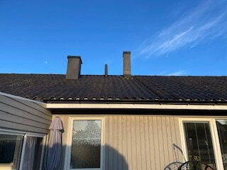 Yttertak av eternit på ett svenskt hus, byggt 1973, med två skorstenar och ljus fasad; färg lossnar efter målning, viss tvätt och underhåll utfört.