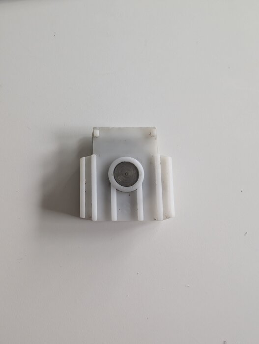 Trasigt hjul från en skjutdörr, monterat i en vit hjulvagga. Hjulet diskuterat i forum för hjälp med att hitta tillverkare och ersättningsdelar.