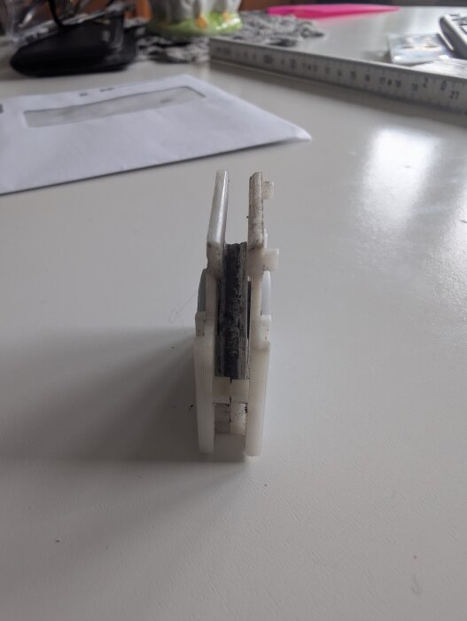 Plastkomponent från skjutdörr med två hjul och en hjulvagga, sedd från sidan på en vit yta.