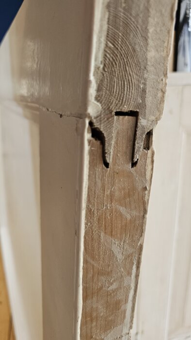 Förskjuten del av trädörrsram från 1932, visar skada i övre vänster hörn orsakad av spänningar över tid, med sikt av träets insida.