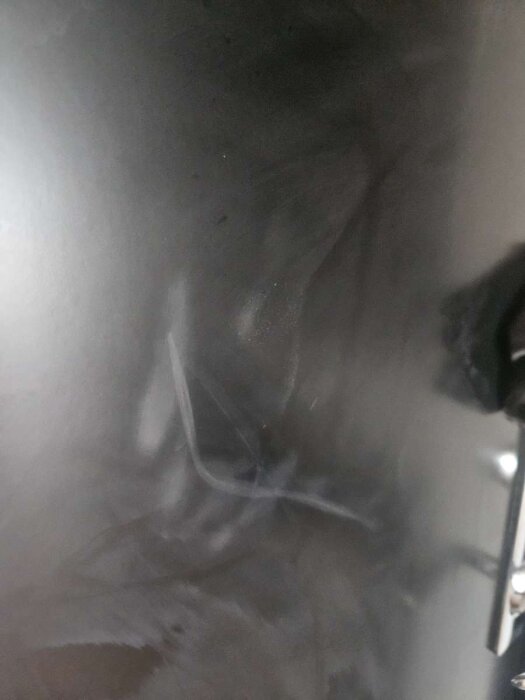 Svart säkerhetsdörr med flera grova repor på ytan.