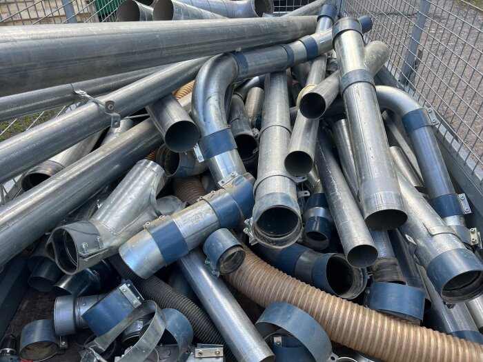 Hög med metallrör och kopplingar i olika storlekar, troligen för användning i ett ventilations- eller spånsuganläggningsprojekt.