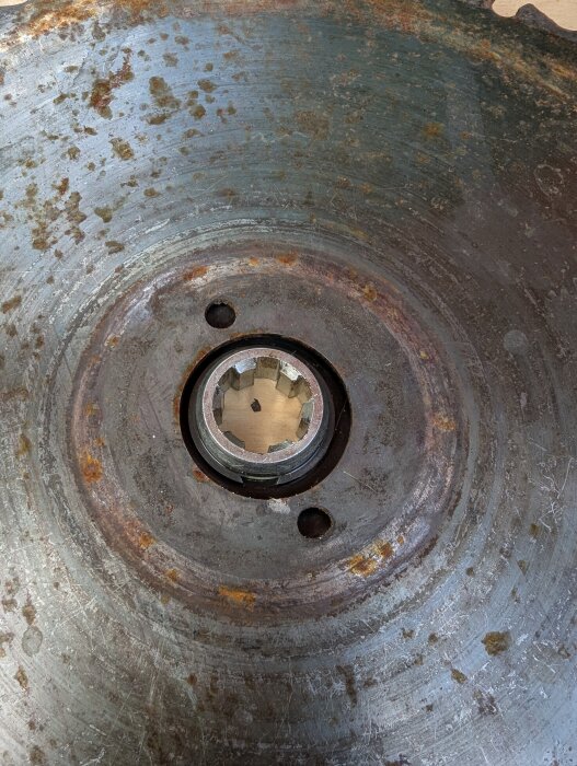 Rostig sågklinga med centrerat hål, omgiven av slitage och rostfläckar, använd för Husqvarna 252rx, hålets diameter större än stödflänsen.