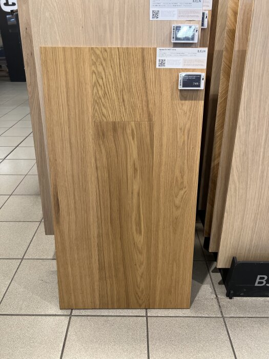 Trägolvprov i ek med synlig ådring visas på ett golvföretags utställning, med prisskylt och teknisk information intill.