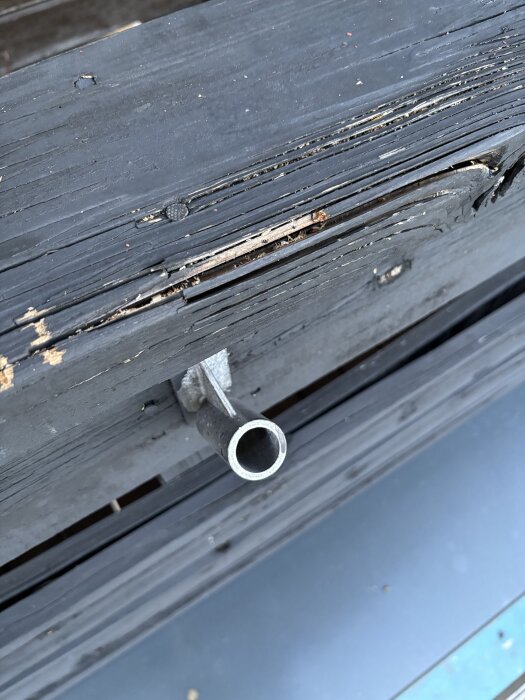 Solskadat trästaket med sprickor och en metallhållare vid terrass.