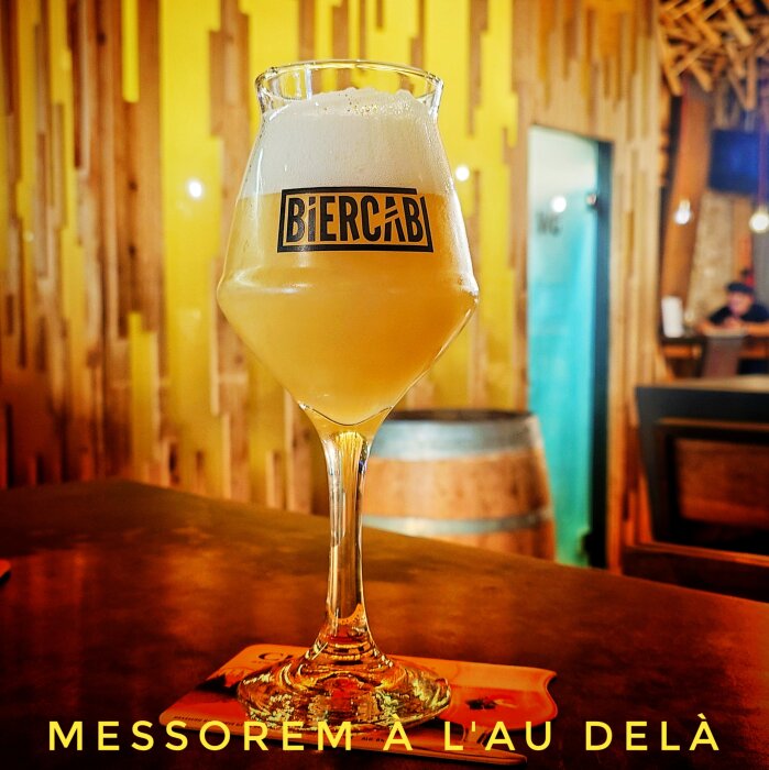 Ett glas öl på ett bord med etiketten från Biercab, i en mysig bar.