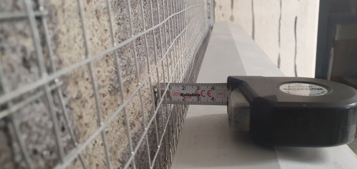 Byggvägg med nät och måttband som visar 2 cm djup på kortvägg för putsning.