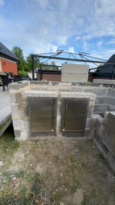 Murade väggar med två rostfria luckor installerade, del av ett oklart uteköksprojekt under uppbyggnad.