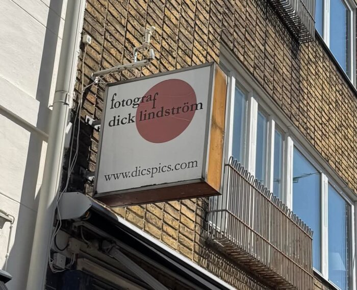 Skylt på tegelvägg med texten "fotograf dick lindström" och webbplatsen "www.dicspics.com".