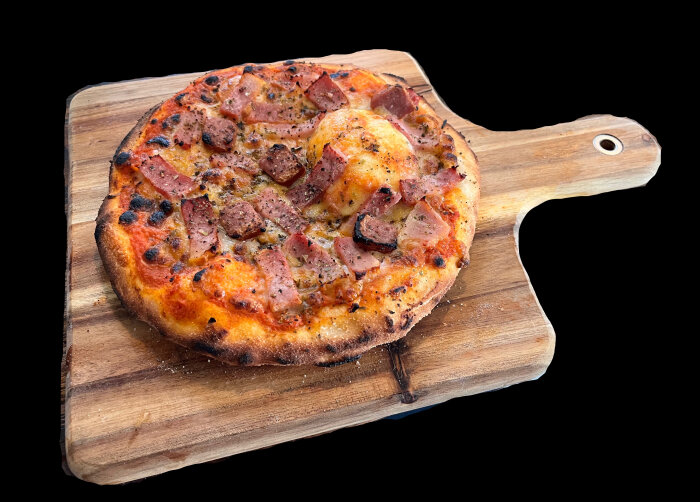 Kebabpizza med ost och grönsaker på en träskärbräda.