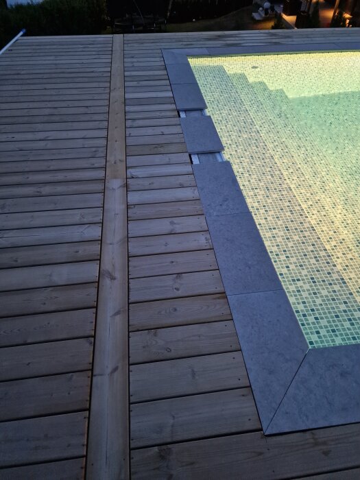 Stensarg runt en pool, visad i skymningsljus med delvis ojämna skarvar mellan stenarna. Trädäck omger poolområdet.