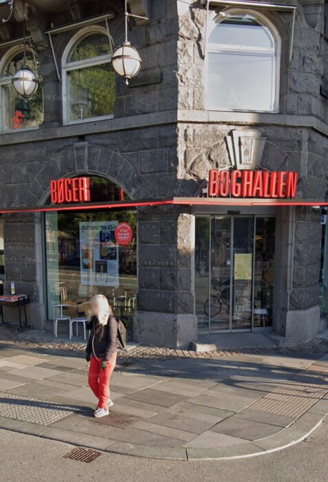 Fasad av bokhandel med skylten "Boghallen" och "Bøger", en person promenerar förbi.