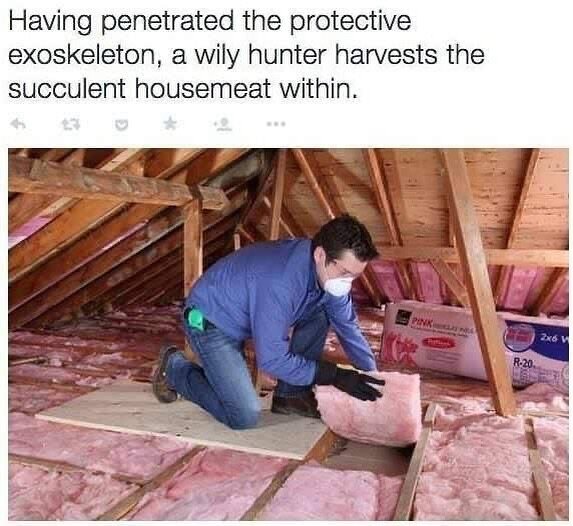 En person i vinden lyfter en bit fiberglasisolering.