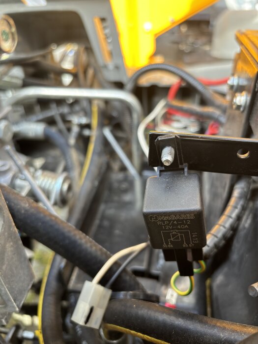 Ett fordonsbatteriområde med olika kopplingar och ett relä, del av en felsökning av elektricitet i en byggmaskin.