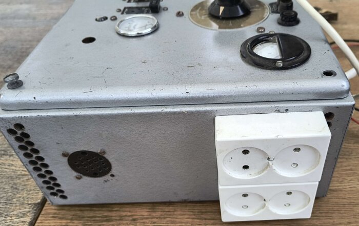 Gammal elektrisk apparat med mätare och uttag, borttagen från ett hobbyrum i en BRF från 50-talet, visas på ett bord.