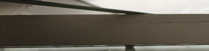 En skadad dörrkarm med synlig spricka, grund mot ett uterum. Dörren behöver repareras, slipas och målas.