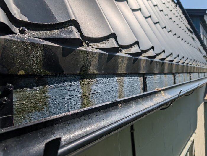 Takfot med svart takplåt och en delvis monterad hängränna; fotplåt ser för kort ut.