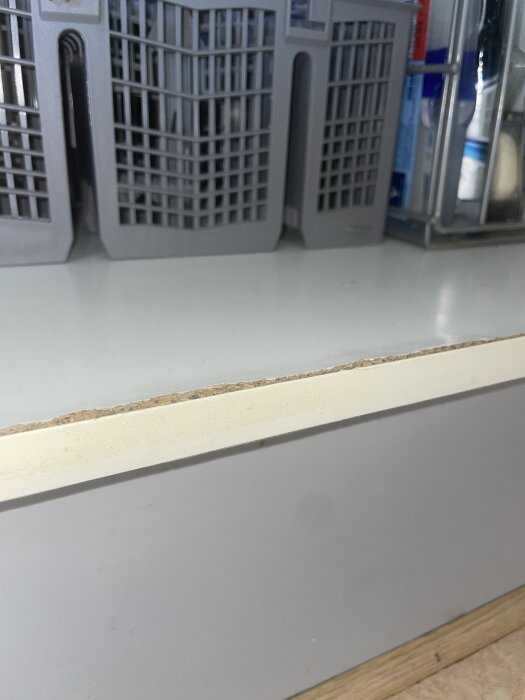 Hyllplan med skadad kant i ett skåp, diskussion om att spackla, slipa, måla eller byta kantlist.