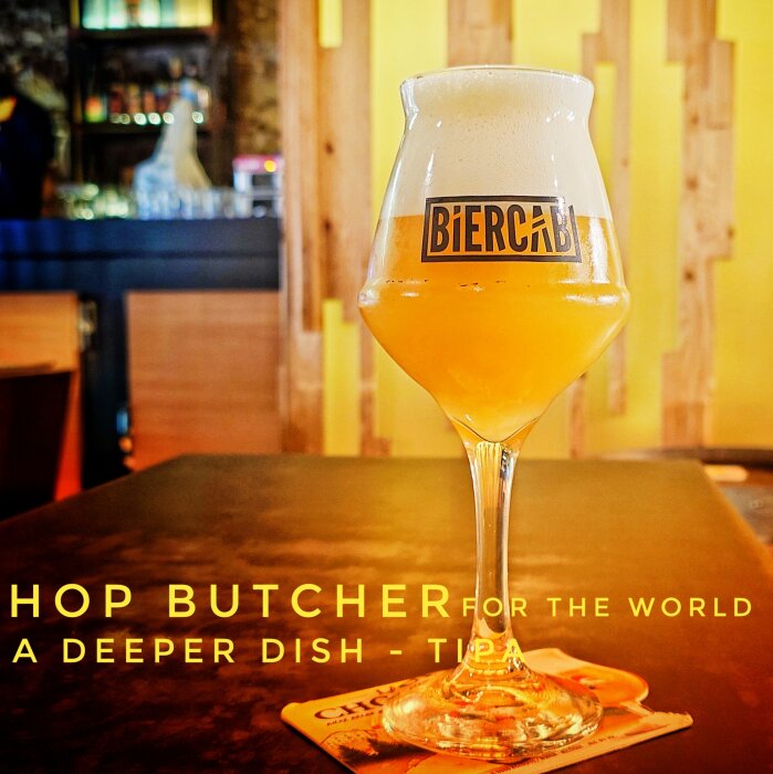 Ett ölglas med TIPA från Hop Butcher for the World, Chicago, på ett bord i en rustik bar eller restaurangmiljö.