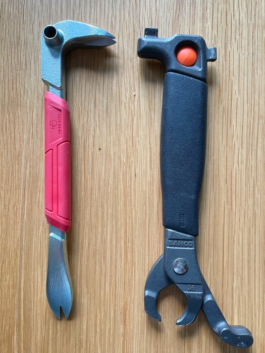 Två spikutdragare på ett träbord, en med rött handtag och en med svart handtag märkt Bahco, används vid renovering av fritidshus.