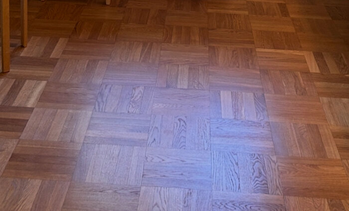 Rutparkettgolv i ek, delvis utbytt till faner och behandlat med hårdvaxolja, visas i dämpad belysning.