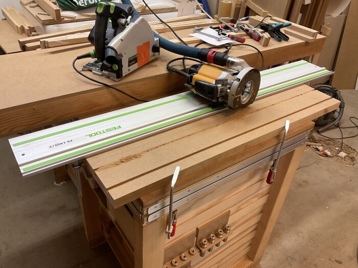 Sänksåg och fräs med styrskena på arbetsbänk, omgiven av verktyg och bearbetade MDF-skivor.