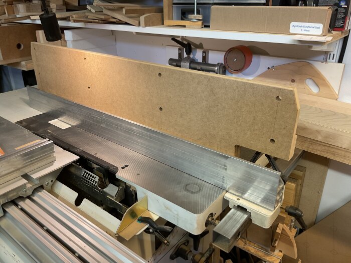 Högt anhåll av mdf på justersåg i verkstad, med kringliggande verktyg och arbetsmaterial.