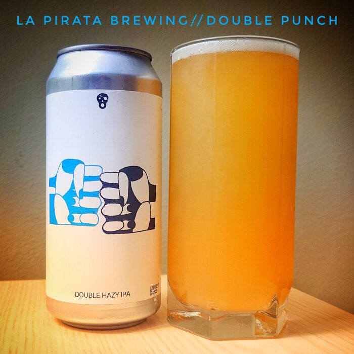 En burk La Pirata Brewing Double Punch och ett glas med gul-orange hazy IPA på ett bord.
