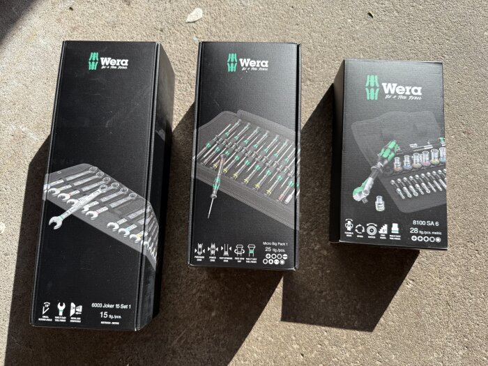 Tre kartonger med verktygssatser från Wera på ett golv, inkluderar nycklar och bits.
