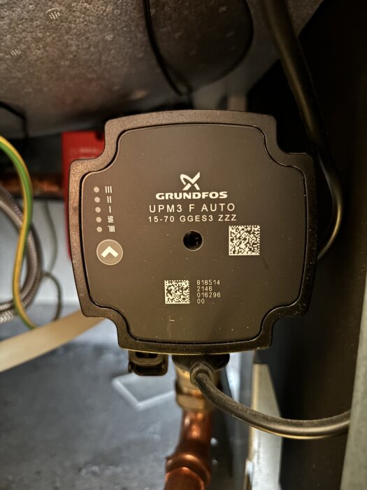 Nibe F370 heat pump's circulation pump, label showing "Grundfos UPM3 F Auto 15-70 GGES3 ZZZ," with visible QR codes and wiring.