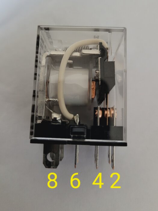 Genomskinligt relä med fyra numrerade anslutningar (8, 6, 4, 2) som syns tydligt.