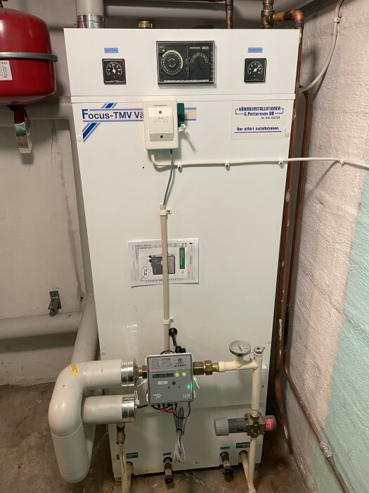 En äldre fjärrvärmecentral med rör och mätare, tillverkad av Focus-TMV Värme, installerad av C. Pettersson AB.